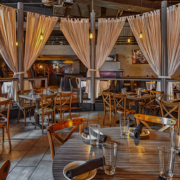 Flavio Restaurant DC's dining room with tables set, wooden chairs, and sheer curtains creating private sections.