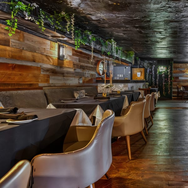 Flavio Restaurant DC dining room with black tablecloths, light chairs, and wood paneling with hanging greenery.